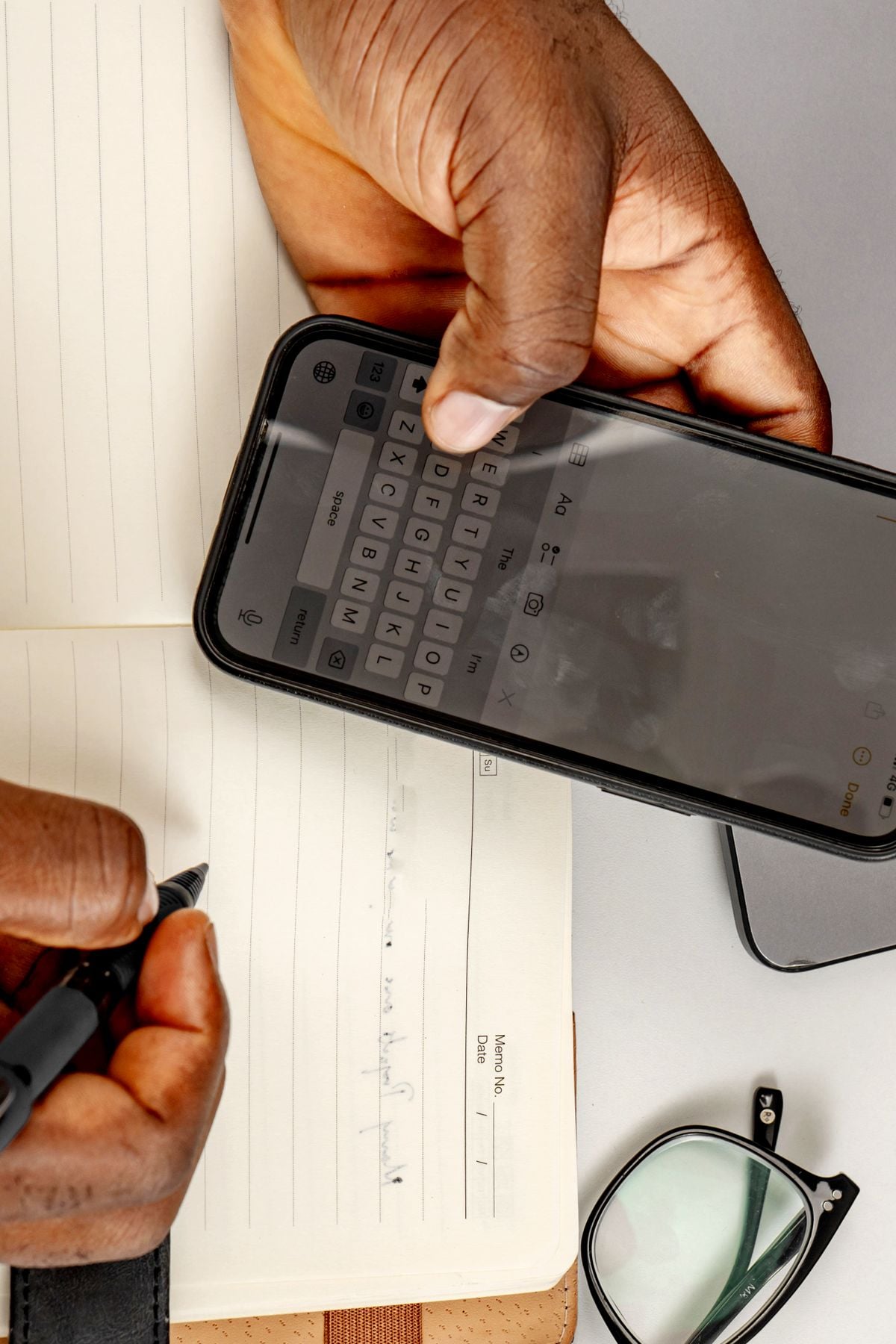 Person journaling beside a smartphone, representing Memoirs' digital wellness tools