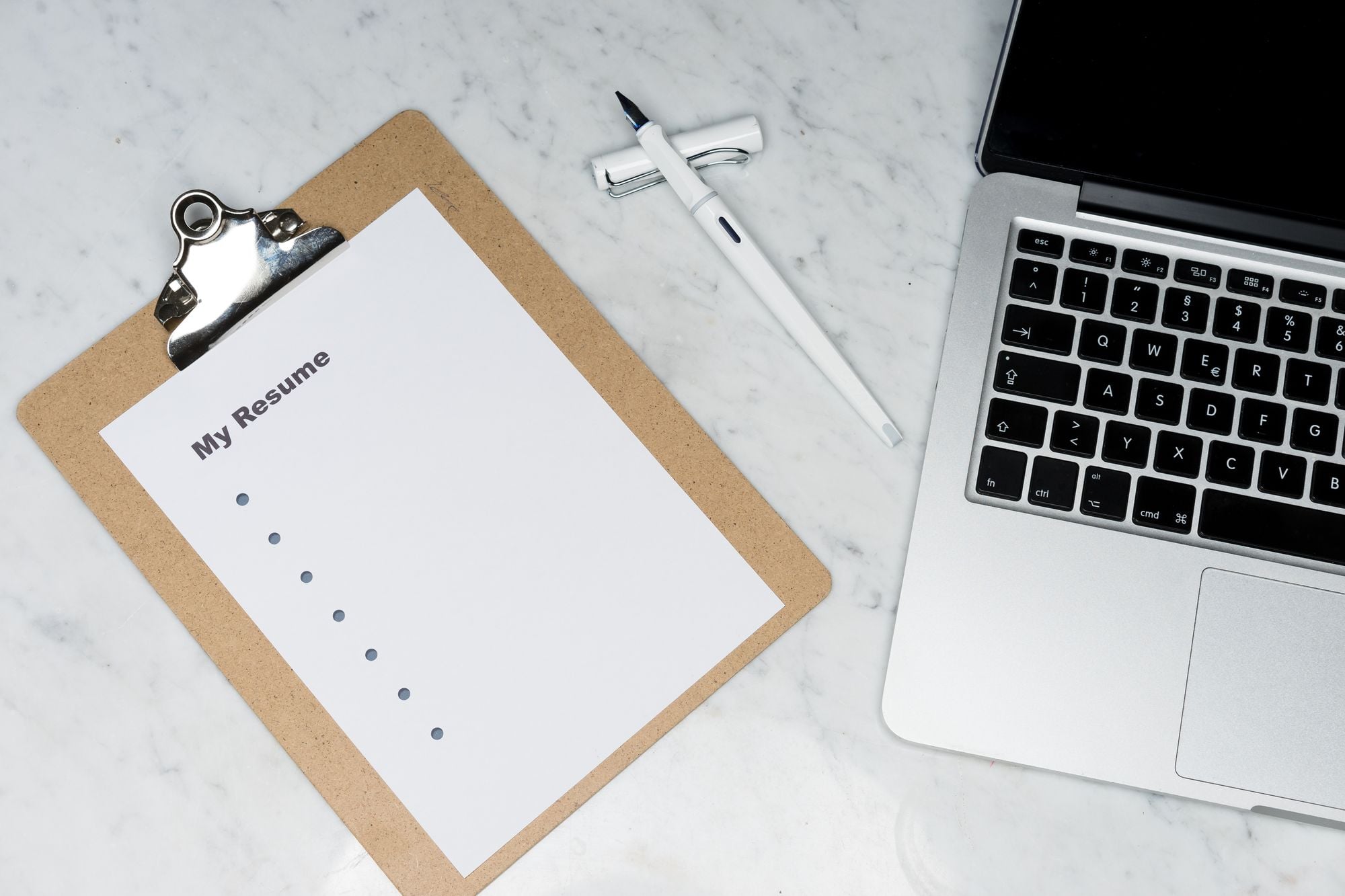Resume, pen and laptop representing Valunique's bias-aware hiring workflow